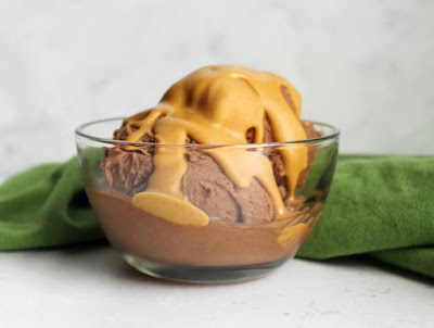 Peanut butter, chocolate and bananas come together to make this dairy free, gluten free, guilt free nice cream treat! It takes almost no effort to make and tastes like a dream! glass bowl of chocolate and peanut butter nice cream scoops with peanut butter magic shell on top