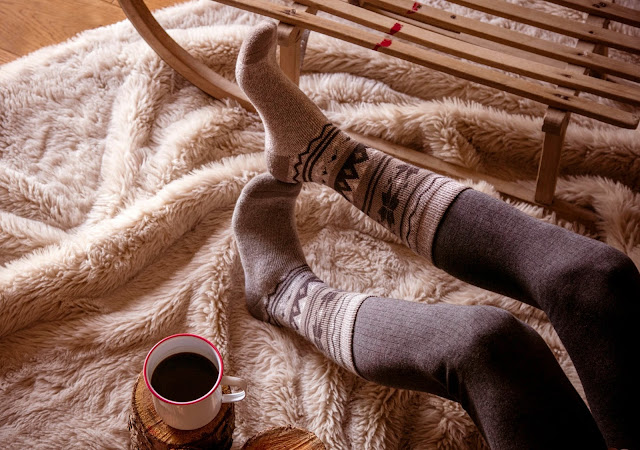 Feet wearing Heat Holder socks on a fur rug. 