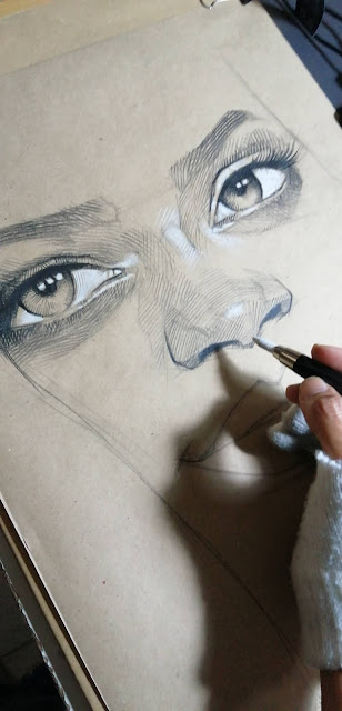 Drawing on a Kraft paper of Rihanna's eyes.  Lines and shadows with black crayon and lights with white.