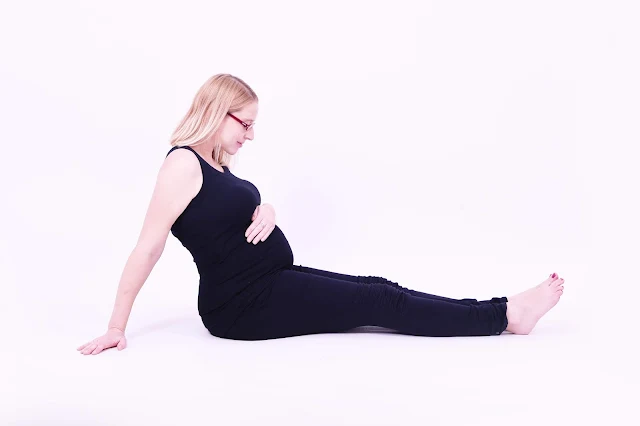 Maternity photo shoot picture at 37 weeks pregnant sitting on the floor in black