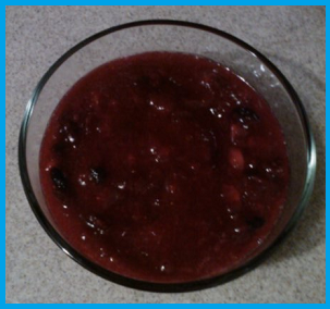 Bright red sauce with some whole berries still visible, contained within a large glass bowl.