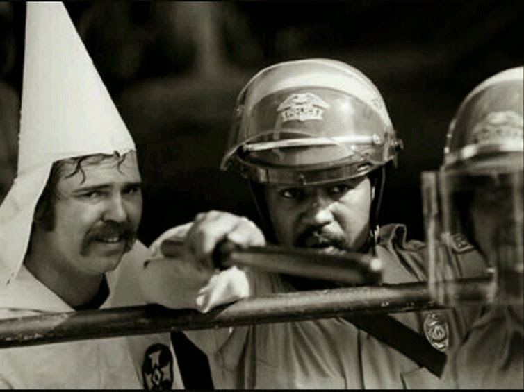 24 Rare Historical Photos That Will Leave You Speechless - A black police officer protects a member of the KKK during a rally in 1983.
