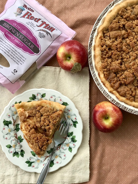 Apple crumb pie with a slice on a serving plate.