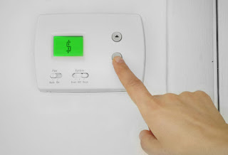 A person turning an a/c unit's temperature down