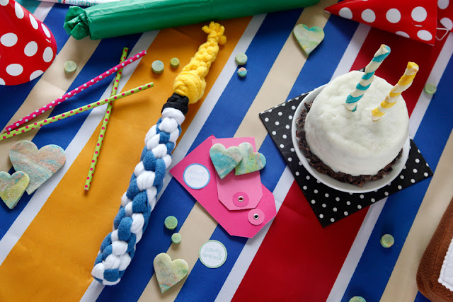 Woven fleece candle dog tug toy on a party table with cake and treats