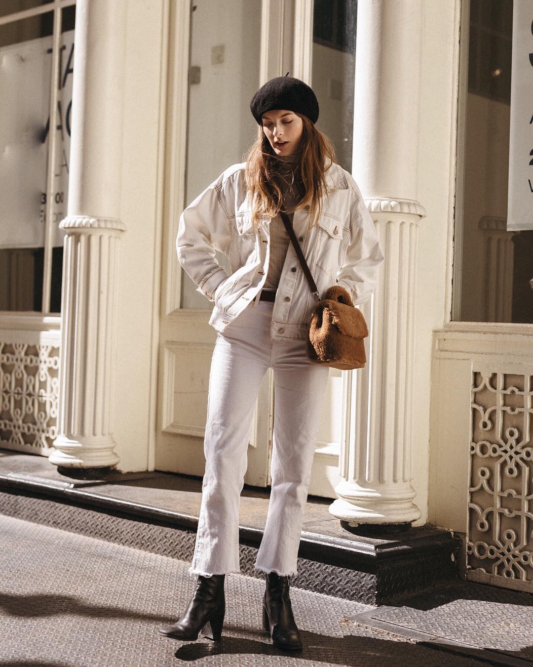 25 of the Best White Denim Pieces for Fall and Winter Outfits— @nycbambi Christie Tyler in a black beret, white denim jacket, camel shearling bag, white raw-hem jeans, and black boots