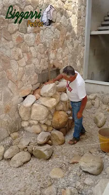 Dia 19 de setembro de 2016, Bizzarri trabalhando na construção da cascata de pedra, com pedra de rio, no lago das carpas com pedra do rio e pedregulho do rio em jardim de inverno na sala de estar da casa em condomínio em Atibaia-SP, com as paredes revestidas com pedra moledo.