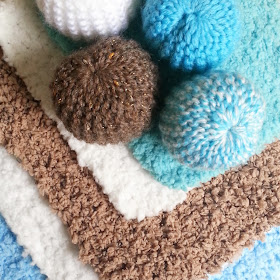 Four one-twelfth scale miniature knitted pouffes on top of four miniature rugs
