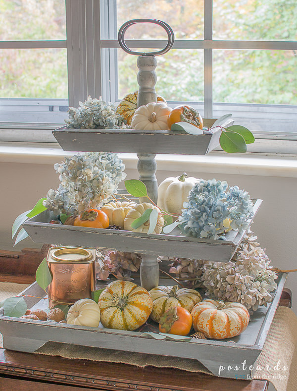 mini pumpkins and dried hydrangeas on a wooden tiered tray