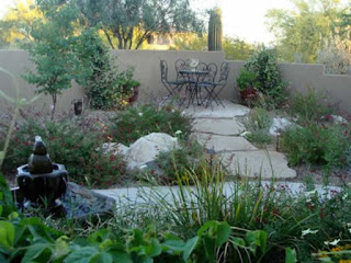 Backyard Xeriscape in Tucson, AZ A backyard with a black fountain left front and plants and stepping stones leading to a small table in the rear