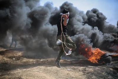 Rapaz lançando objetos incendiário contra israelenses