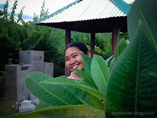 Sweet Smile Woman In Holiday Hiding Behind Fresh Frangipani Green Leaves In The Garden North Bali Indonesia