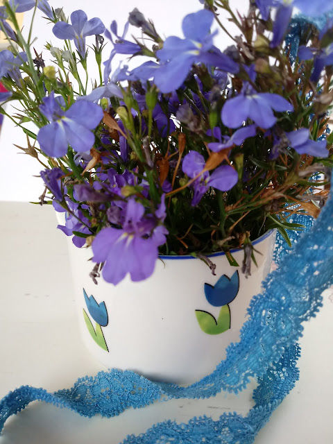 Composición floral de flores azules en taza de color blanco