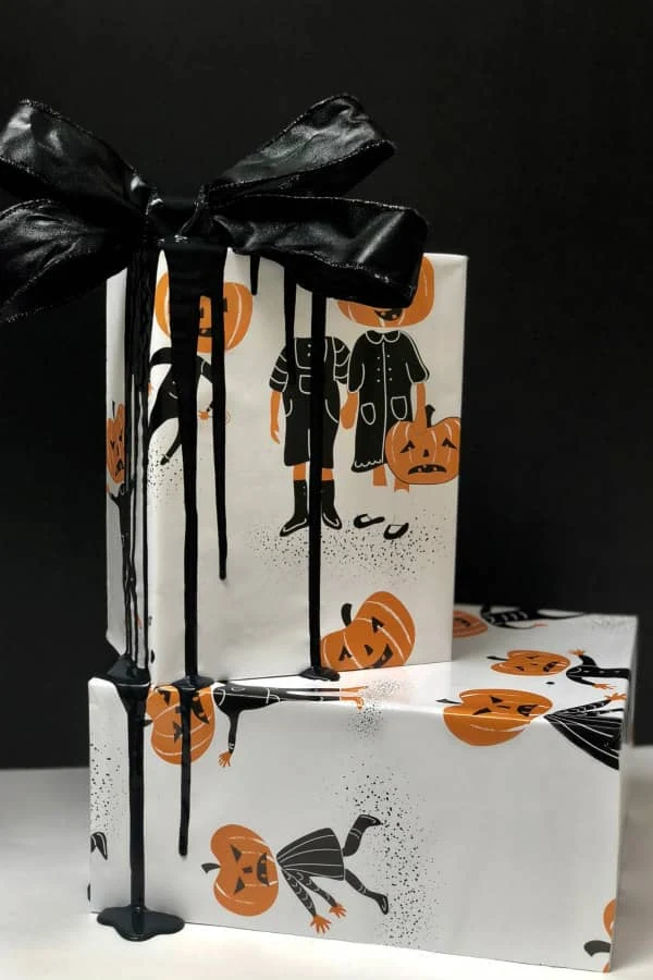 pair of Halloween presents wrapped in pumpkinhead paper with black ribbon and bow
