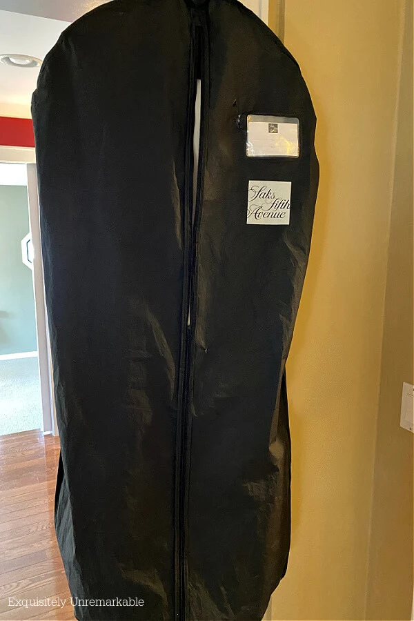 Black garment bag hanging in hallway