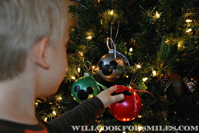 boy touching mickey ornaments on a tree 