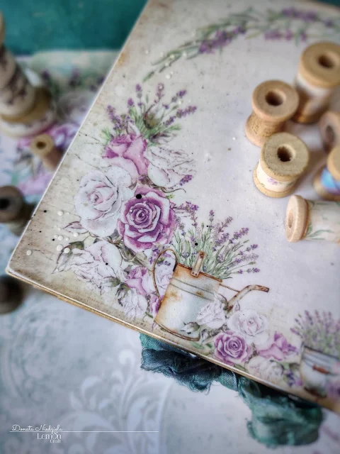 Przepiękna kompozycja w stylu prowansalskim: lawendowy wianek, w który wplecione są fioletowe i białe róże oraz rustykalna konewka i dzbanuszek