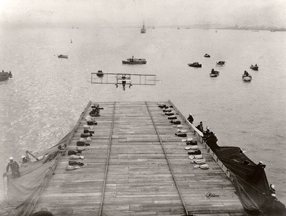 Photo of plane coming in to land on a wooden deck while sailors watch. 1911 Photo of plane coming in to land on a wooden deck while sailors watch. 1911