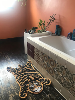 A bathmat in the shape of a tiger.