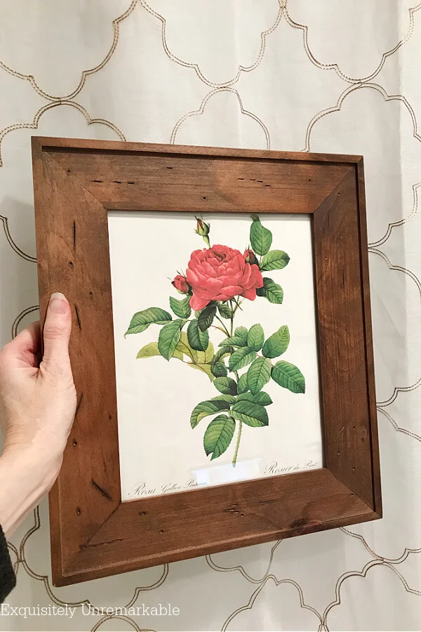 Framed rose print held up to a shower curtain in the bathroom