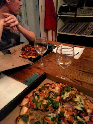Dining table with pizzas and wine glasses on it.