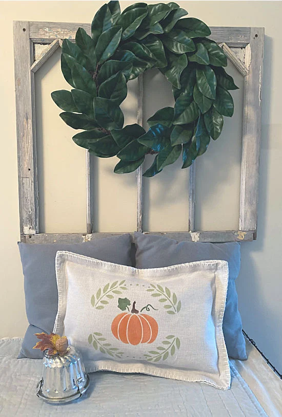 stenciled pumpkin pillow and vintage window with wreath