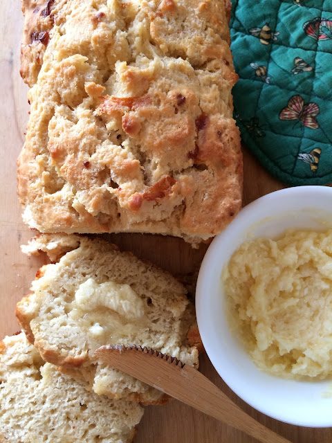 Honey cheddar beer bread with slices being spread with honey butter.