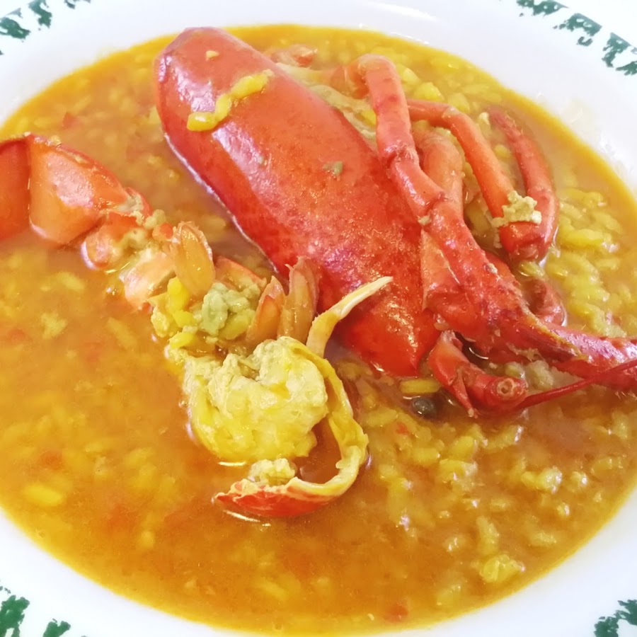 un plato de arroz meloso con medio bogavante