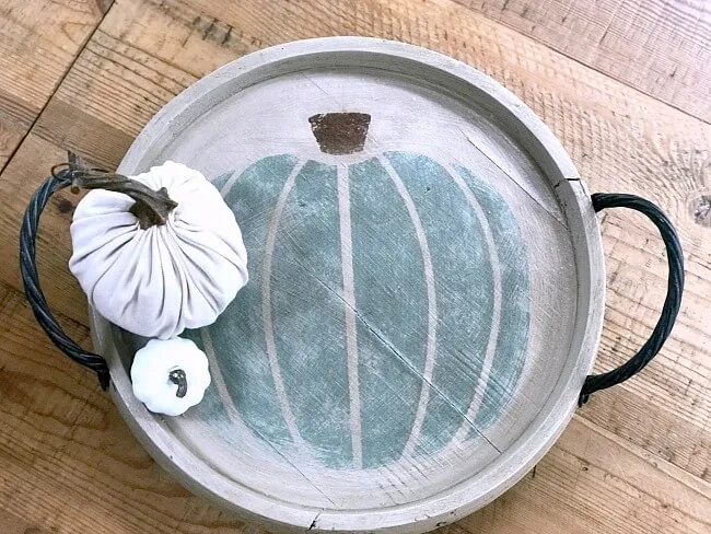 Round stenciled pumpkin tray with 2 white pumpkins on it