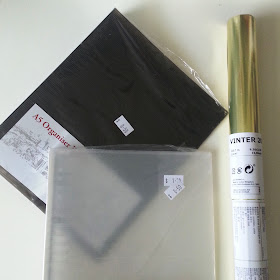 Two plastic folder covers: ine brown and one clear, and a roll of gold giftwrap.