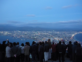 Night / Twilight view of Hakodate and it's sparkling lights and ocean from Mt Hakodate with crowd of people in the foreground