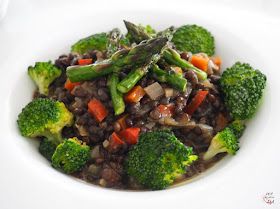 Guiso vegetariano de lentejas caviar, o lentejas beluga, con verduras y ras el hanout, con brócoli y puntas de espárragos trigueros.