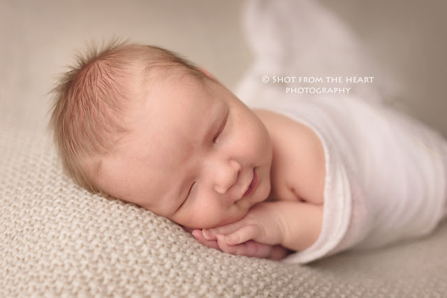 newborn baby boy sleeping on cream blanket in side pose