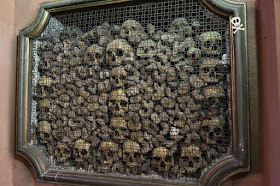 Marco abierto en la pared lleno de calaveras y huesos largos en composición casi artística.