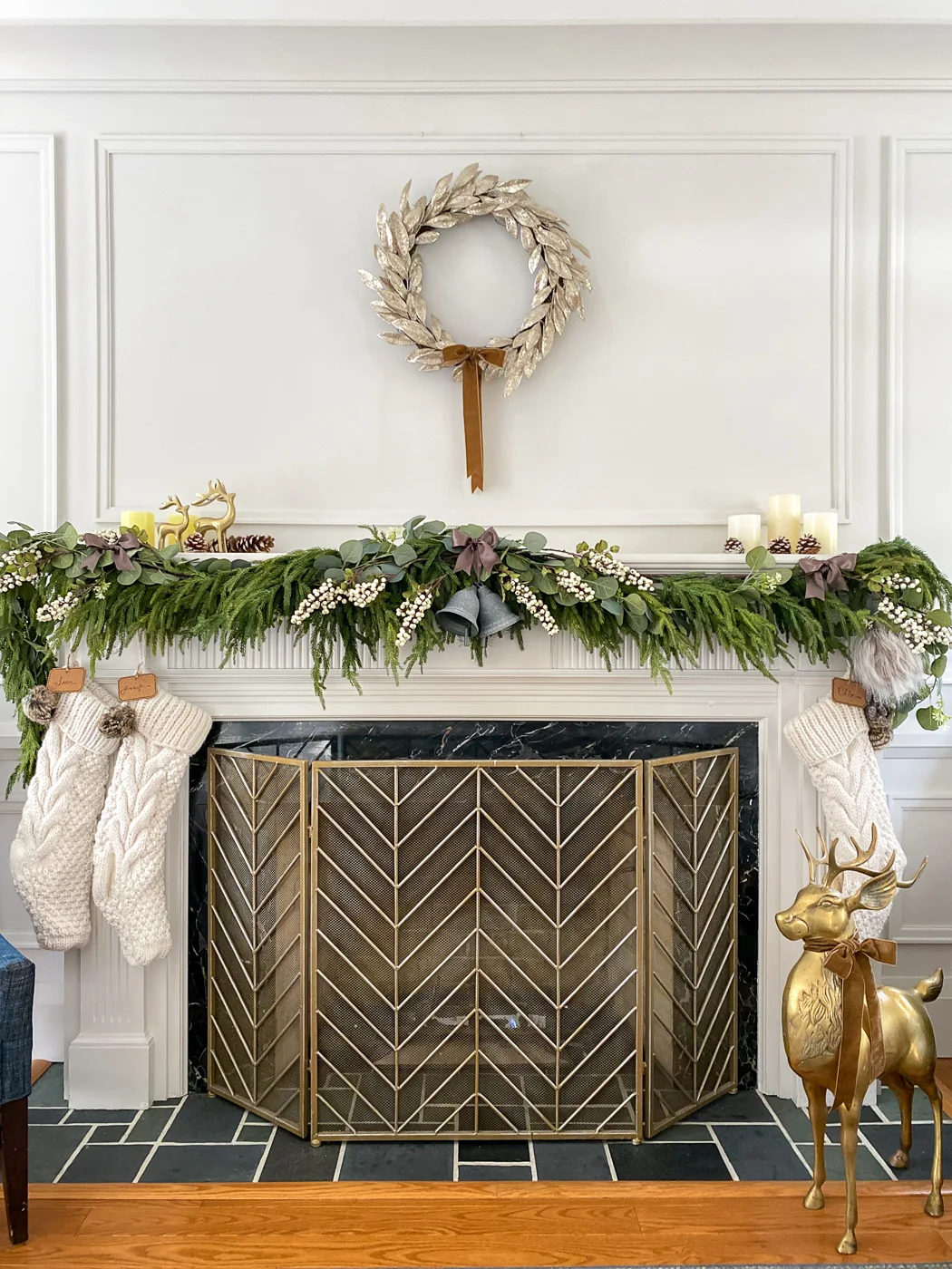 elegant christmas mantel with white berries, brass deer, and gold wreath