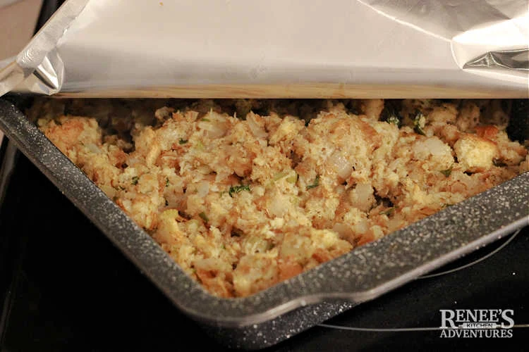 Sage and Onion Stuffing in pan after baking with corner of foil pulled back.