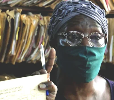 Jemilat Keshinro, a records officer at the Lagos General Hospital, Marina, holds up the hospital card of a suspected COVID-19 patient.