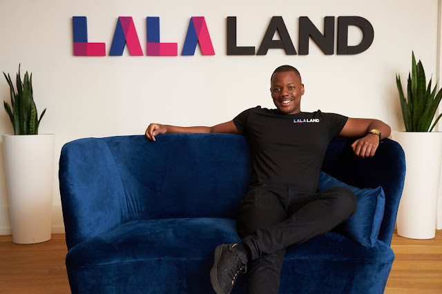 Michael Musandu zittend op een blauwe bank met het Lalaland-logo achter hem.