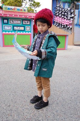 Niño perdido en el zoológico leyendo un mapa de ubicación