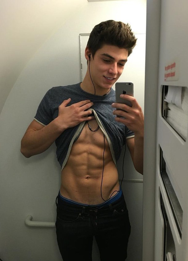 cute-shirtless-male-model-abs-smiling-airplane-bathroom-selfie