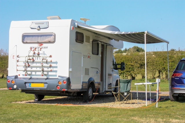 Photo of the back of the motorhome with the awning up and a table and chair underneathPhoto of the back of the motorhome with the awning up and a table and chair underneathPhoto of the back of the motorhome with the awning up and a table and chair underneath