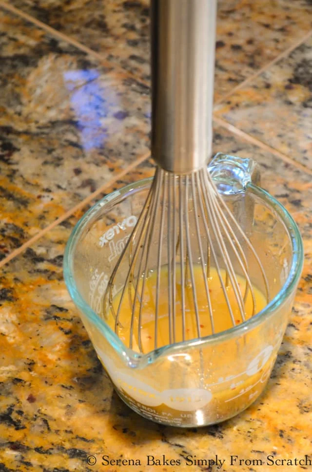 Tangy Dressing in a glass measuring cup with a whisk.