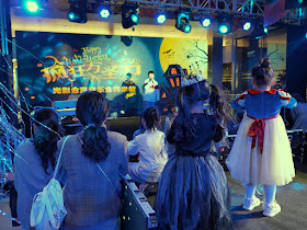people watching a boy sing a song on a Halloween-themed stage