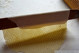 image of a piece of lefse being lifted off the pastry cloth with a stick