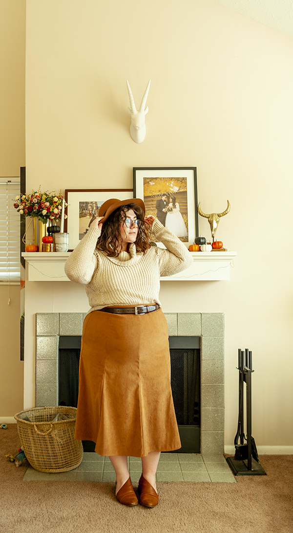 An outfit consisting of a brown panama hat, a cream cowl neck sweater half tucked into a brown A-line tea length skirt and a cognac d'orsay flats.