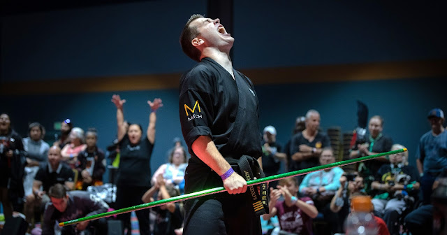 Jackson Rudolph at a competition, yelling while holding a bo staff.