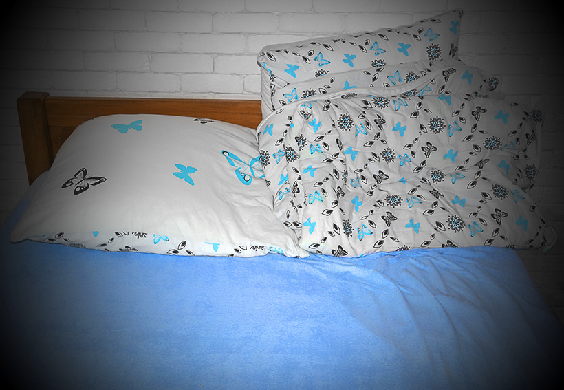 Sen - łóżko z niebieskim prześcieradłem i poduszki w motylki