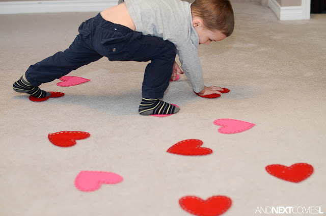 Child with hands and feet on red and pink felt hearts as part of a Valentine's Day gross motor activity