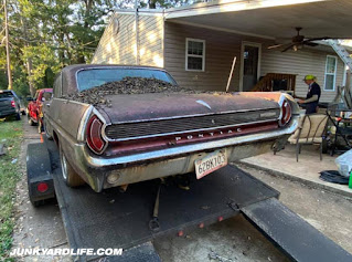 Distinctive 1962 Pontiac tail lights ride high in air of Grand Prix loaded on flatbed trailer.