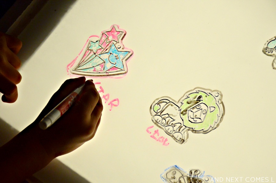Writing and labeling dollar store sun catchers on the light table from And Next Comes L